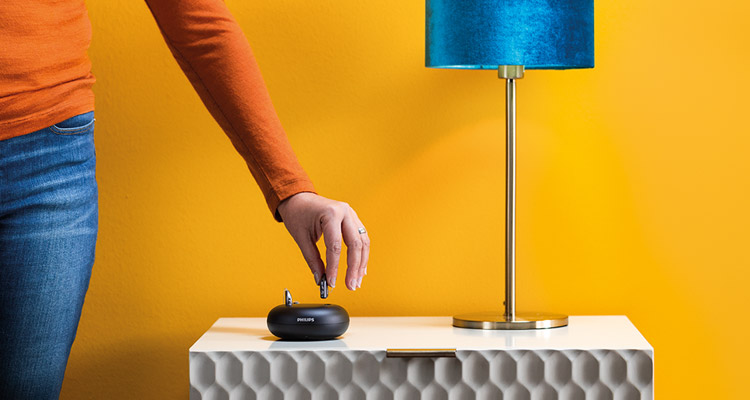 这位女士把她的可充电飞利浦Hearlink助听器放入充电器。