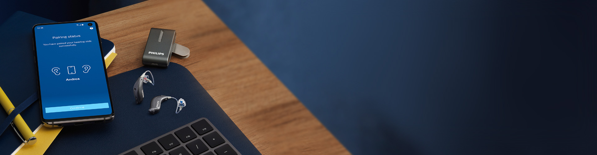 打开了飞利浦HearLink应用软件的智能手机和飞利浦miniRITE 大功率助听器，助听器旁边是飞利浦多功能蓝牙适配器