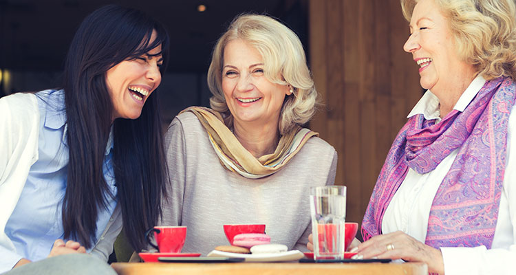 三位女士开心地在户外咖啡馆里消磨时间，聊天时彼此之间毫无困难，互相领会。