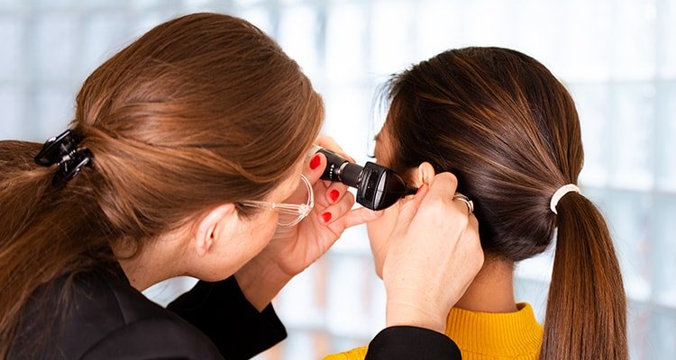 一位听力专业人士正在用耳镜检查顾客的耳道。