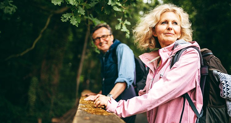 Husband and wife are hiking in the forest and enjoying the sound of nature helping them to relax