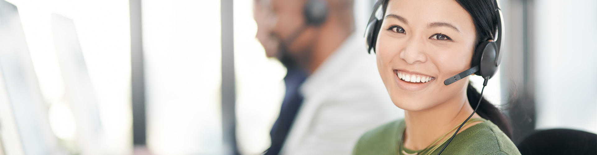 一位女士正通过电话沟通来帮助一位顾客使用助听器。